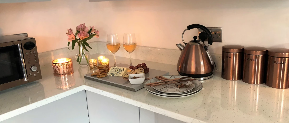 A modern kitchen with high-gloss grey cabinets, a dark tiled floor, and copper-coloured accessories.