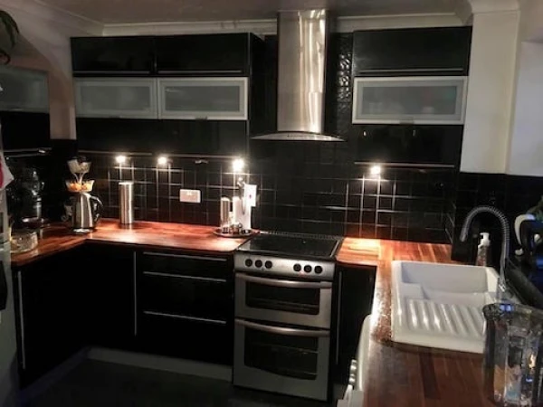 Before image of a kitchen with black cabinets, featuring a dated design and layout prior to a modern transformation.
