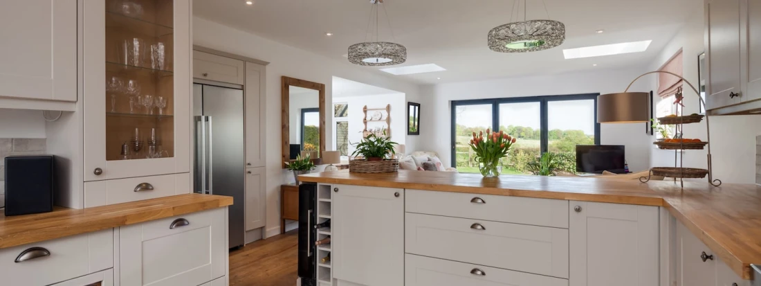 White wood Chelsea style kitchen with oak‑effect countertops, shaker cabinetry and bright open layout.