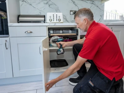 Kitchen fitter attaching a kitchen door using a screwdriver