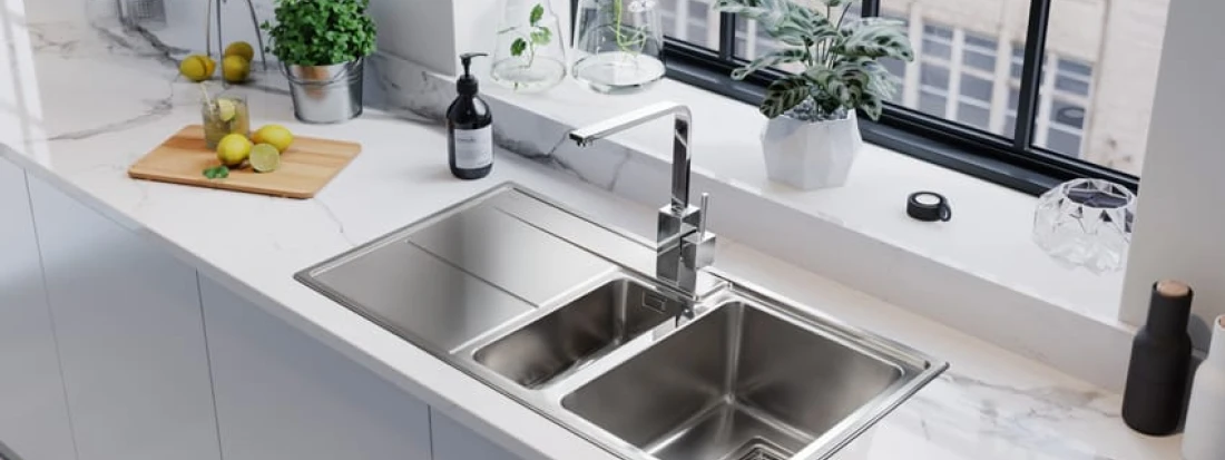 Light grey handleless kitchen with Arlington sink, marble countertops and silver accents.