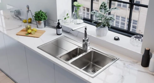 Light grey handleless kitchen with Arlington sink, marble countertops and silver accents.